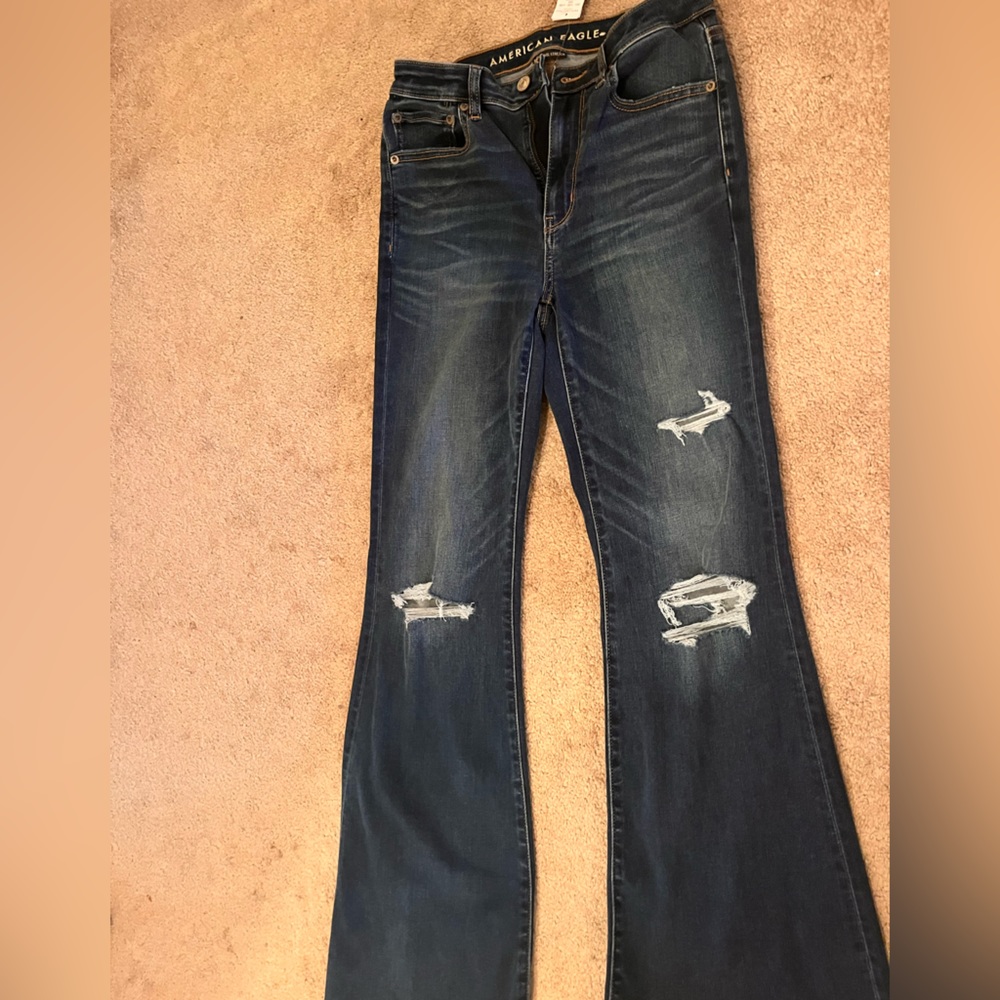Stretch bootcut jeans with distressed and rips at knee.